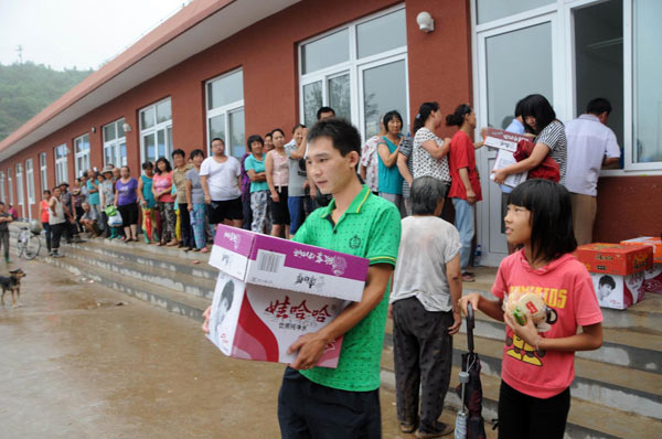 Flood-affected residents of Beicheying Village, Qinglonghu Township line up to receive relief foodstuffs in Fangshan District, a suburb of Beijing, capital of China, July 26, 2012.[Photo/Xinhua] 