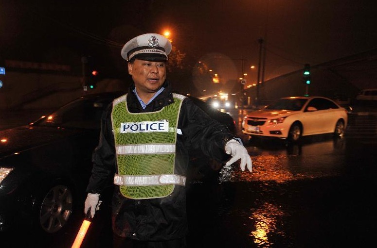 Policeman Nan Jingtao directs traffic in rain in Beijing, capital of China, July 27, 2012. A new round of torrential rain pelted the capital Friday evening. 