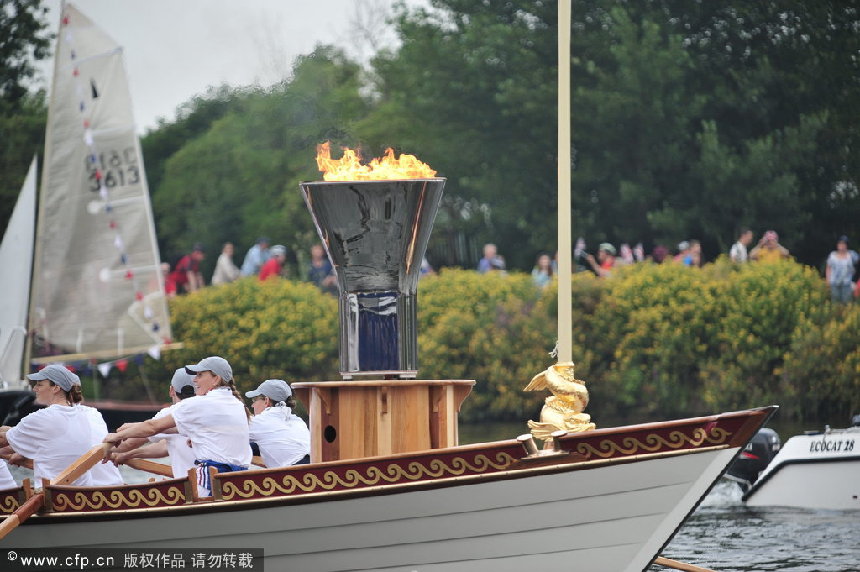 The Olympic flame is carried by the Royal Barge Gloriana on its route along the River Thames from Hampton Court to the Olympic stadium in Stratford, East London ahead of the start of the Olympic Games in the capital. [CFP]