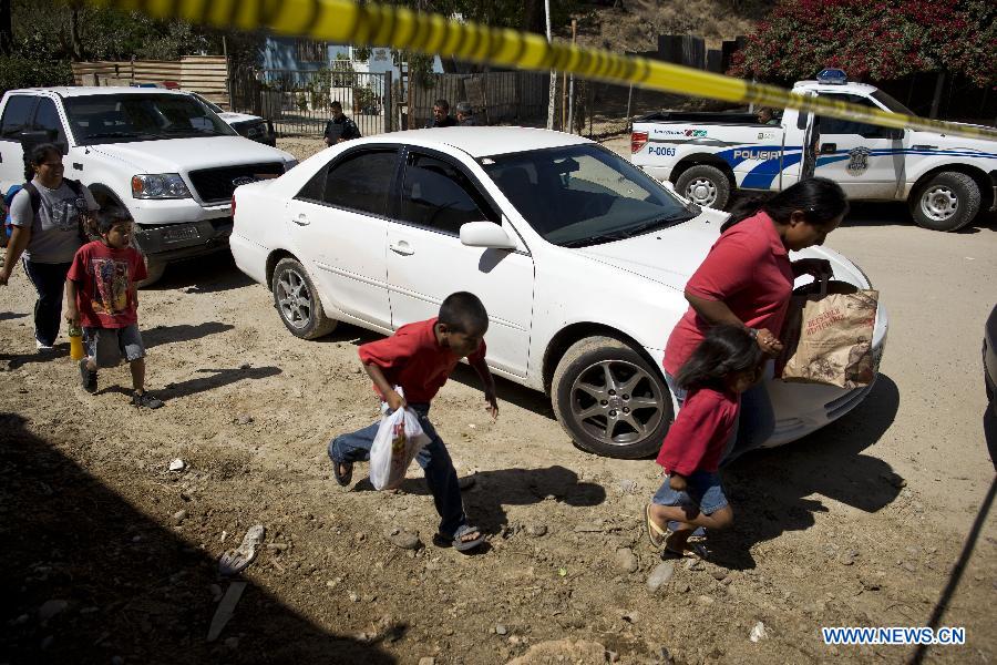 Residents walk near the security perimeter of a crime scene where two men were killed inside a house in Tijuana, northeast Mexico, July 28, 2012. Two high-caliber weapons were found at the crime scene. (Xinhua/Guillermo Arias) 