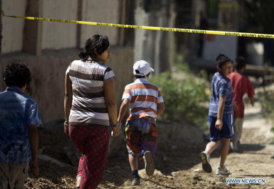 Residents walk near the security perimeter of a crime scene where two men were killed inside a house in Tijuana, northeast Mexico, July 28, 2012. Two high-caliber weapons were found at the crime scene. (Xinhua/Guillermo Arias) 