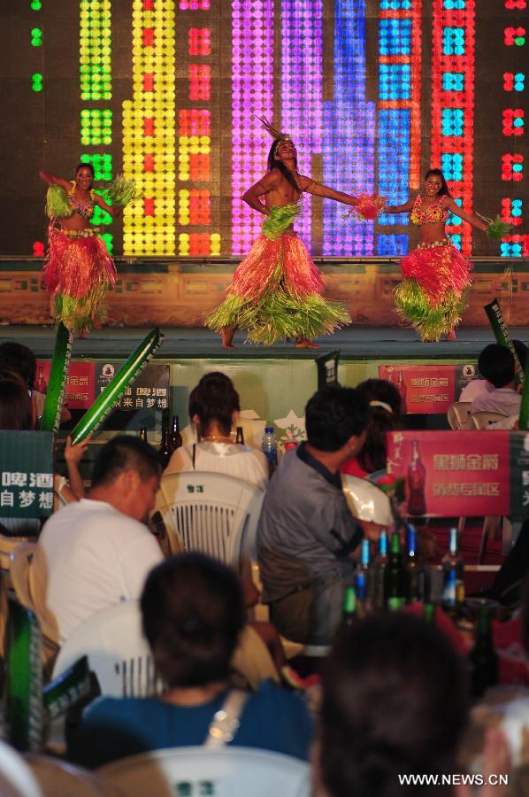 Visitors watch a dance performance while enjoying beer at the 14th China International Beer Festival in Dalian, northeast China's Liaoning Province, July 26, 2012. The 12-day beer festival which opened Thursday at Dalian's Xinghai Square attracted more than 30 Chinese and foreign beer manufacturers with over 400 beers. (Xinhua/Pan Yulong) 