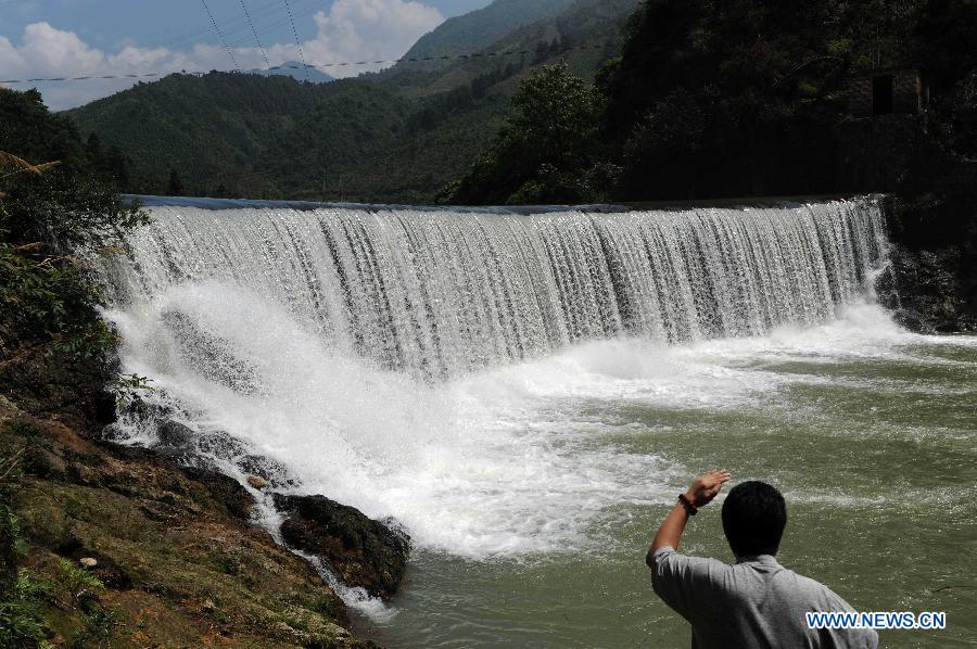 A tourist looks at a small waterfall in Tianhu Scenic Spot of Quanzhou County, south China's Guangxi Zhuang Autonomous Region, July 29, 2012. The Tianhu Scenic Spot, with the height of over 1,600 meters above sea level, is a lake district containing 13 reservoirs and high mountain forests. (Xinhua/Liu Guangming)