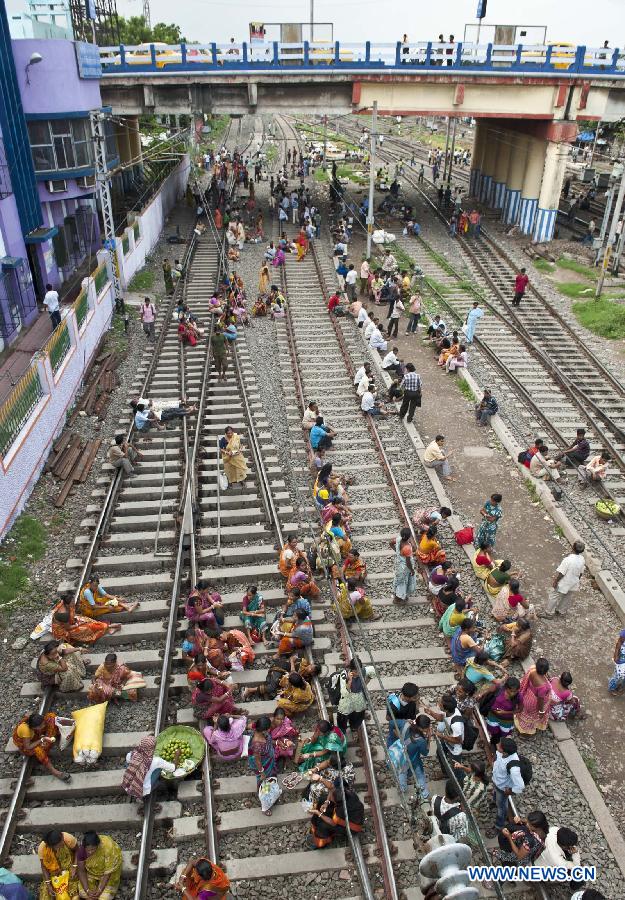 Indian passengers sit on a track waiting for electricity to be restored at a railway station in Calcutta, capital of eastern Indian state West Bengal, India, July 31, 2012. More than half of Indian population were affected Tuesday after a massive power outage hit the country for the second day in a row.
