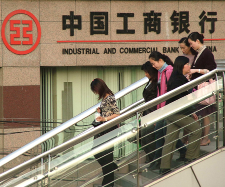 People pass an Industrial and Commercial Bank of China outlet in Shanghai.  The Industrial and Commercial Bank of China and three other lenders will be fined and face other punishment for failing to obey rules regarding the reporting of risk exposure and possible fraud cases.