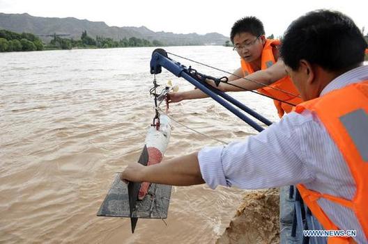 Staff members of a hydrologic station measure the flux of water in the Yellow River in Zhongwei City, northwest China's Ningxia Hui Autonomous Region, July 31, 2012. [Xinhua] 