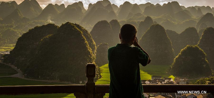 A visitor takes photos of Wanfenglin in Xingyi, southwest China's Guizhou Province, July 31, 2012. Wanfenglin, which literally means Forest of Ten Thousand Peaks, is a national geological park and also a tourism attraction in Xingyi City. (Xinhua/Liu Xu)