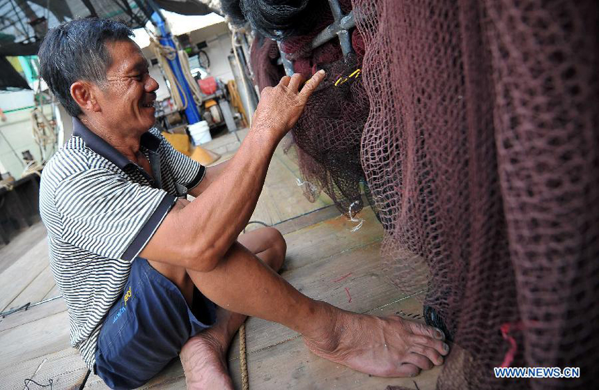 A fisherman fixes a fishing net in Tanmen Town of Qionghai, south China&apos;s Hainan Province, July 31, 2012. As the two-and-half-month summer fishing moratorium in the South China Sea ended Wednesday, fishing boats will be back to work. 