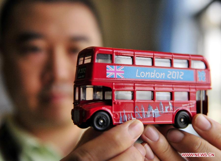 A staff member of Zindart Manufacturing Limited shows a double-decker bus model made for London Olympic Games in Dongguan, south China's Guangdong Province, Aug. 1, 2012. A total of 700,000 identity card straps and more than 2.5 million franchised souvenirs were made by Dongguan's manufacturing companies for London 2012 Olympic Games. [Xinhua]