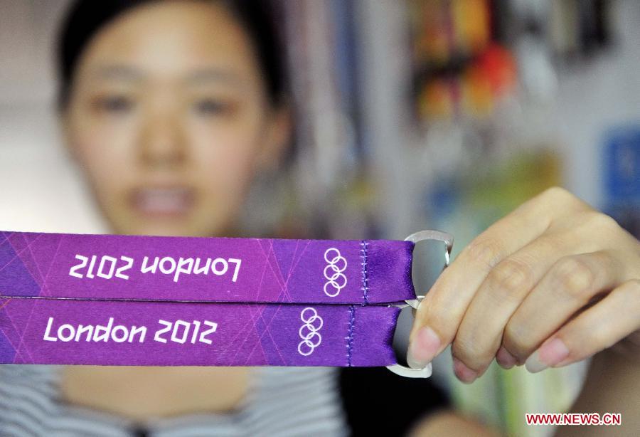 A staff member of Dongguan Zhanhong Weaving String CO., LTD. shows two identity card straps made for participants of London Olympic Games in Dongguan, south China's Guangdong Province, Aug. 1, 2012. A total of 700,000 identity card straps and more than 2.5 million franchised souvenirs were made by Dongguan's manufacturing companies for London 2012 Olympic Games. [Xinhua]