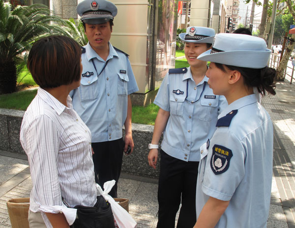 Ding Tao(second from the left), a chengguan who has a master's degree, works with his colleagues to persuade a peddler near Shanghai's bustling Nanjing Road to move on. [ Photo / China Daily ]