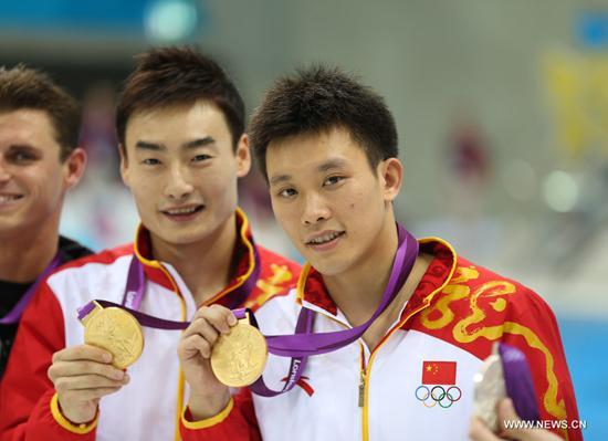 Qin Kai (L)/Luo Yutong of China pose at the awarding ceremony of men's synchronised 3m springboard event at the London 2012 Olympic Games in London, Britain, Aug. 1, 2012. The Chinese divers claimed the title in this event. [Xinhua]