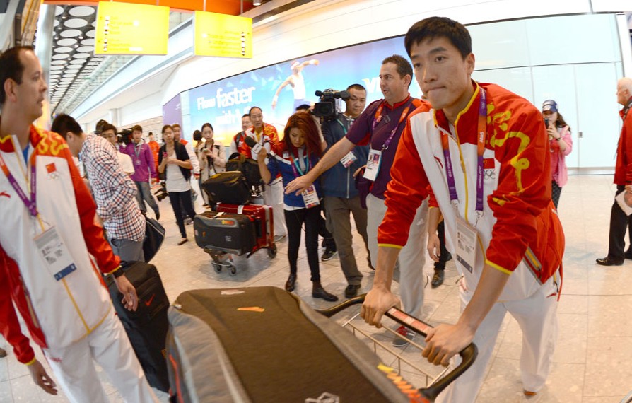 China's 110m hurdler Liu Xiang poses for pictures with a fan after his arrival at Heathrow airport in London, Britain, on August 3, 2012. Liu Xiang will compete in men's 110m hurdles competition of athletics at the London 2012 Olympic Games. [Xinhua]