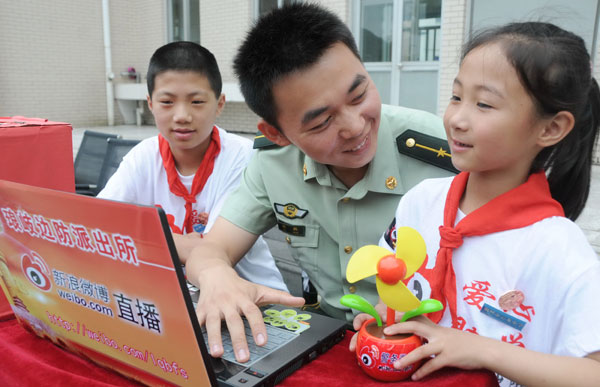 Chen Hang, an officer of the Mawei district border defense brigade in Fuzhou, capital of Fujian province, shows local primary students how to update a micro blog. Chen runs the official micro blog for his brigade. [Photo / Xinhua]