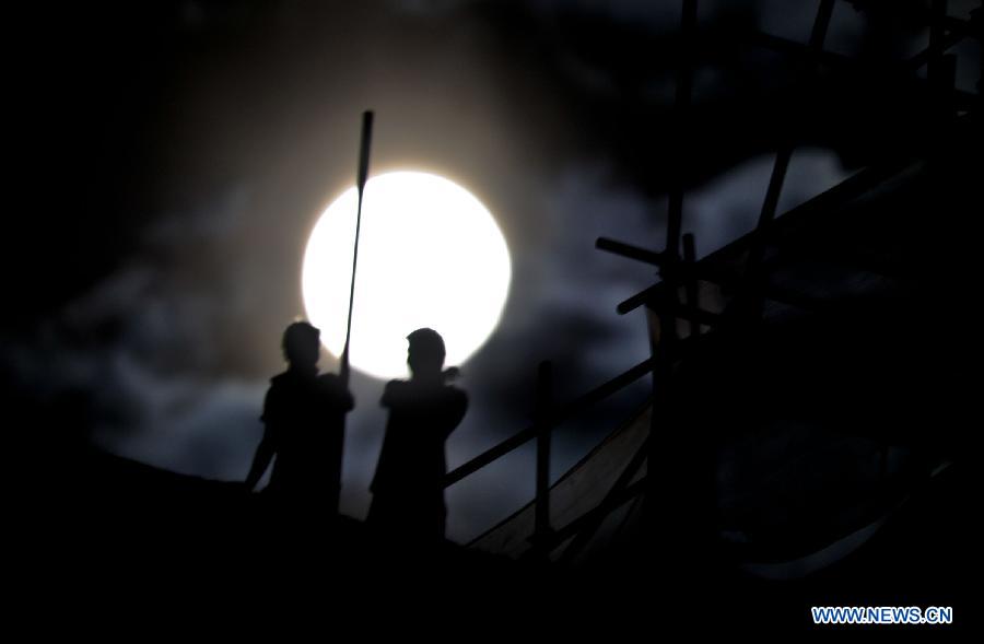 Two persons are busy in the moonlight in Lhasa, capital of southwest China's Tibet Autonomous Region, Aug. 2, 2012. The moon shined brightly at night on Thursday. (Xinhua/Purbo Zhaxi) 