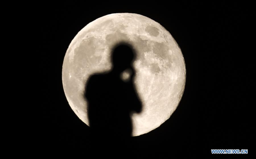 A person talks on the phone in the moonlight in Lhasa, capital of southwest China's Tibet Autonomous Region, Aug. 2, 2012. The moon shined brightly at night on Thursday. (Xinhua/Purbo Zhaxi) 