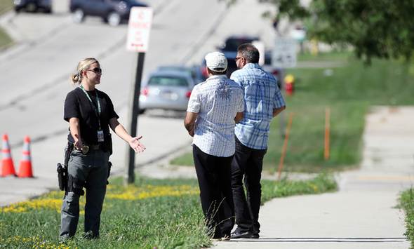 A policewoman speaks to passersby near the Sikh Temple of Wisconsin where at least one gunman fired upon people at a service on August, 5, 2012 Oak Creek, Wisconsin. At least six people were killed when a shooter, who was later shot dead by a police officer, opened fire on congregants in the Milwaukee suburb. [Xinhua]