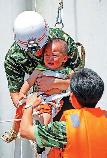 Rescuers save a child trapped by floods in Benxi, Liaoning province, on Monday. [China Daily]