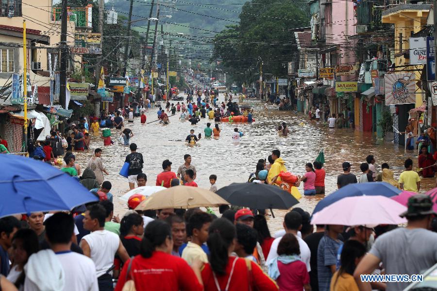 Residents wade through the flood in Marikina City, the Philippines, Aug. 8, 2012. Eleven people died, while over one million were displaced as torrential rains brought by the southwest monsoon flooded large parts of Metro Manila and nine provinces in northern and central Philippines.