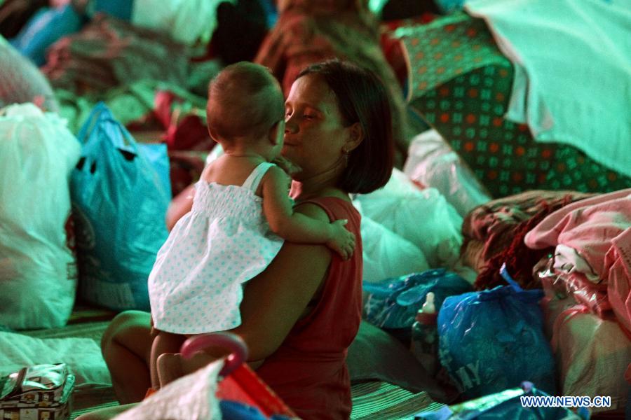 A mother carries her child inside an evacuation center in Marikina City, the Philippines, Aug. 8, 2012. Eleven people died, while over one million were displaced as torrential rains brought by the southwest monsoon flooded large parts of Metro Manila and nine provinces in northern and central Philippines.