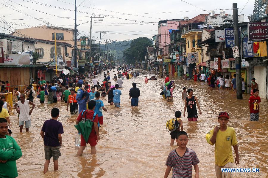 Residents wade through the flood in Marikina City, the Philippines, Aug. 8, 2012. Eleven people died, while over one million were displaced as torrential rains brought by the southwest monsoon flooded large parts of Metro Manila and nine provinces in northern and central Philippines.