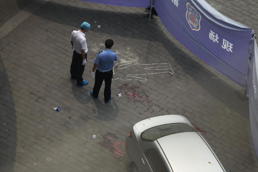 Policemen obtain evidence at the scene of an armed robbery in front of a bank in southwest China's Chongqing Municipality, Aug. 10, 2012. One person was shot dead and two others were injured in an armed robbery in Chongqing Municipality Friday morning. Police have launched a manhunt for the serial killer believed to be behind the robbery.