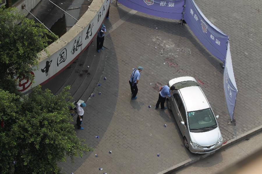 Policemen obtain evidence at the scene of an armed robbery in front of a bank in southwest China's Chongqing Municipality, Aug. 10, 2012. One person was shot dead and two others were injured in an armed robbery in Chongqing Municipality Friday morning. Police have launched a manhunt for the serial killer believed to be behind the robbery.