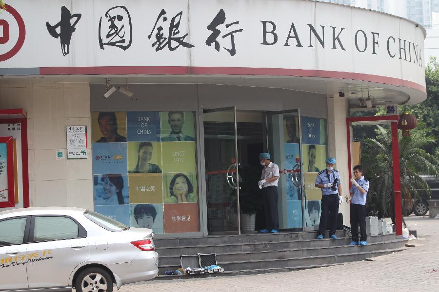 Policemen obtain evidence at the scene of an armed robbery in front of a bank in southwest China's Chongqing Municipality, Aug. 10, 2012. One person was shot dead and two others were injured in an armed robbery in Chongqing Municipality Friday morning. Police have launched a manhunt for the serial killer believed to be behind the robbery.