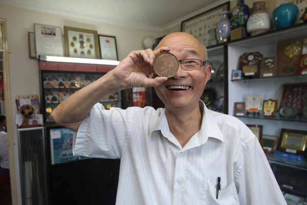 Chen Hongkang has a huge collection of Olympic and other Games medals and badges that he wants to share with other hobbyists. [Photo by Zhang Xinyan / for China Daily]
