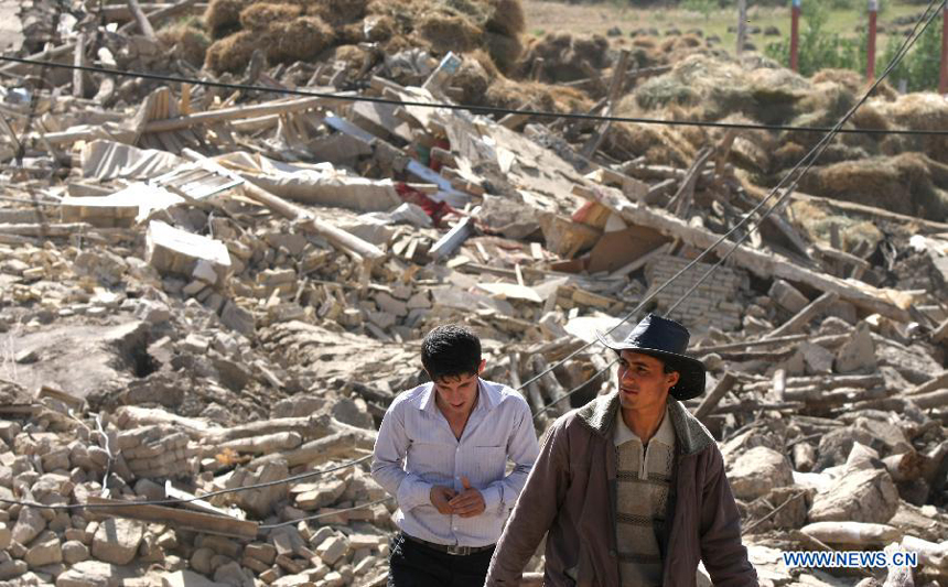 Two men walk past the destroyed buildings after an earthquake in Varzaqan in northwest Iran, on Aug. 12, 2012. The death toll of Saturday&apos;s strong twin quakes in northwest Iran has risen to some 300, the semi- official Fars news agency cited an official as saying on Sunday. 