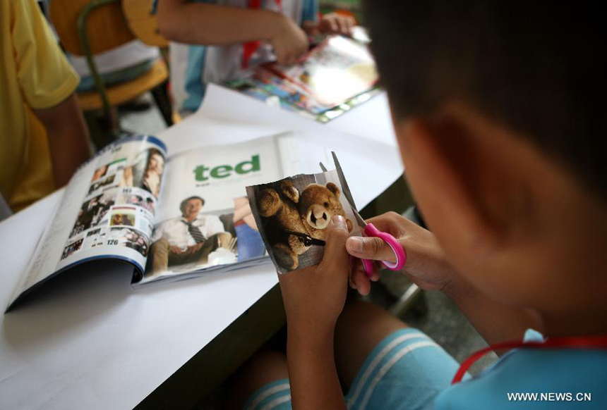 A student cuts a picture from a magazine to patch a big picture about his dream during a charitable activity in Shuren School, a school for the children of migrant workers, in Beijing, capital of China, Aug. 12, 2012.