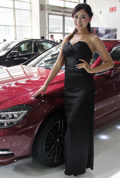 A model stands in front of a car display at the All in Tuning All in Caravaning Show China 2012 on Aug 10, 2012, at the National Agriculture Exhibition Center, Beijing. [Huang Xiaobing/Asianewsphoto]