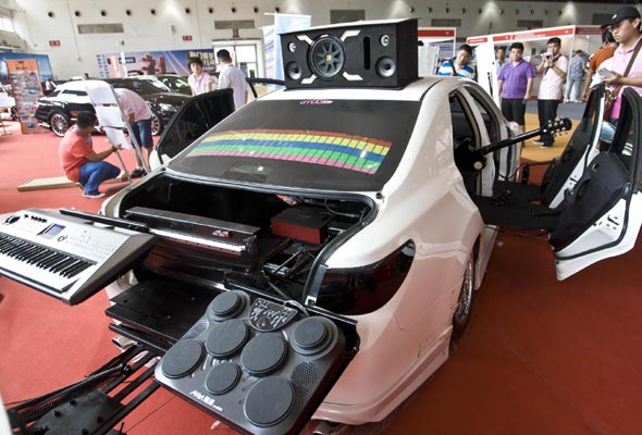 Visitors watch a vehicle that converts into a mobile band at the All in Tuning All in Caravaning Show China 2012, National Agriculture Exhibition Center, Beijing, on Aug 10, 2012. [Photo/Xinhua] 