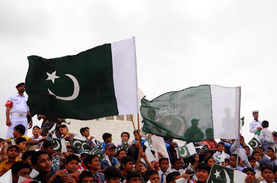 Pakistani people wave national flags at the mausoleum of the founder of Pakistan Muhammad Ali Jinnah during a ceremony to mark Pakistan's Independence Day in southern Pakistani port city Karachi, on Aug. 14, 2012. 