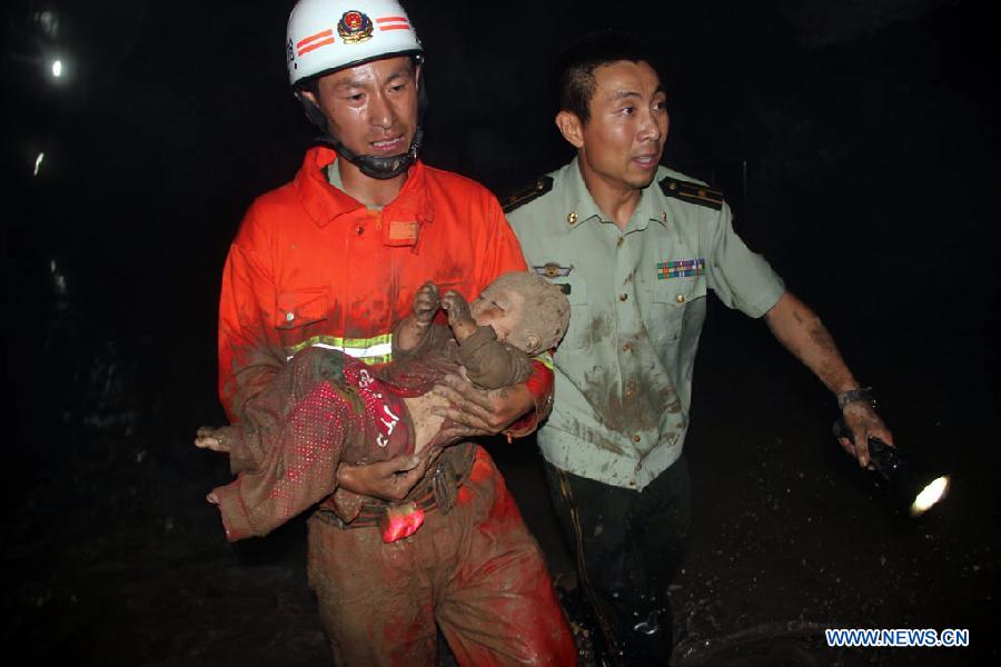 A firefighter rescues a child from an accident site after a road collapsed at Liaoyang Street of Harbin City, northeast China's Heilongjiang Province, Aug. 14, 2012. Two people were confirmed dead and two others injured when a roadbed collapsed at Liaoyang Street in Nangang District of Harbin City on Tuesday. 