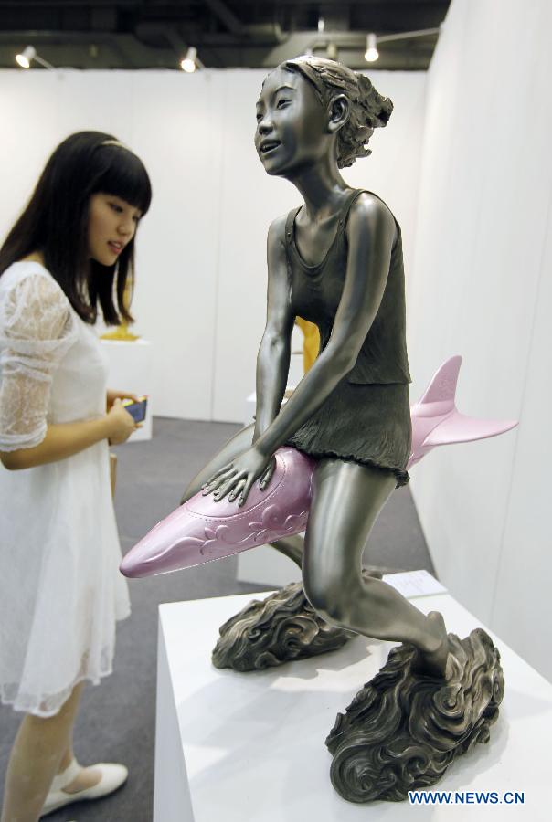 A visitor watches a creative statue at a preview of Beijing Art Expo held in China World Trade Center in Beijing, capital of China, Aug. 15, 2012. The five-day expo, which kicked off on Thursday, displays more than 5,000 art works provided by 90 arts institutions from 16 countries and regions.