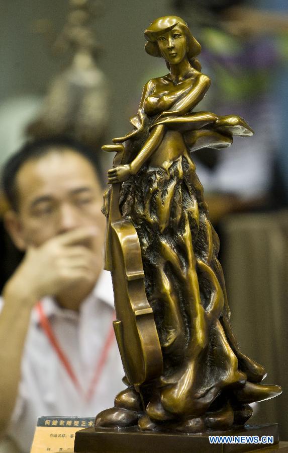 A visitor watches a bronze figurine at Beijing Art Expo held in China World Trade Center in Beijing, capital of China, Aug. 16, 2012. The five-day expo, which kicked off on Thursday, displays more than 5,000 art works provided by 90 arts institutions from 16 countries and regions.