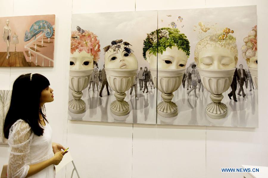 A visitor watches a painting at a preview of Beijing Art Expo held in China World Trade Center in Beijing, capital of China, Aug. 15, 2012. The five-day expo, which kicked off on Thursday, displays more than 5,000 art works provided by 90 arts institutions from 16 countries and regions.