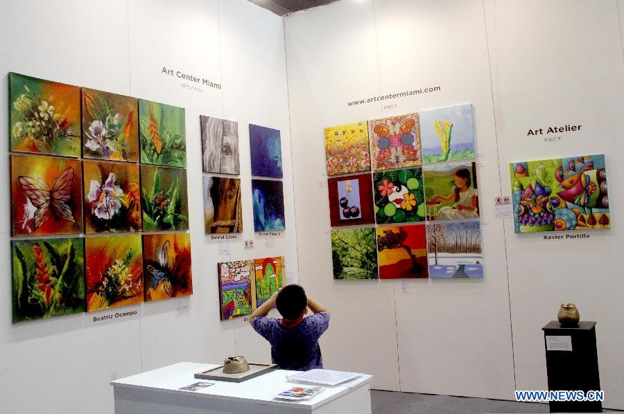 A visitor watches paintings at Beijing Art Expo held in China World Trade Center in Beijing, capital of China, Aug. 16, 2012. The five-day expo, which kicked off on Thursday, displays more than 5,000 art works provided by 90 arts institutions from 16 countries and regions. 