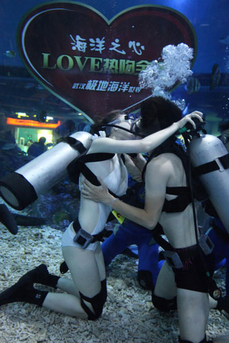 A couple kisses inside an aquarium located in Wuhan, Central China's Hubei province to celebrate Qixi Festival, known as Chinese Valentine's Day, which falls on the seventh day of the seventh lunar month, on Aug 22, 2012. [Photo/Xinhua]