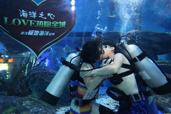 A couple kisses underwater while carrying oxygen tanks on their backs inside an aquarium in Wuhan, on Aug 22, 2012. [Photo/Xinhua]