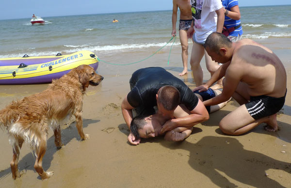 An Australian applies first aid to save a man pulled from the sea in Yantai, Shandong province, on Sunday. The Australian and his dog helped pull the man to the beach, who, after regaining consciousness, was taken by ambulance to a hospital. PHOTO BY SHI LIGUO / FOR CHINA DAILY 