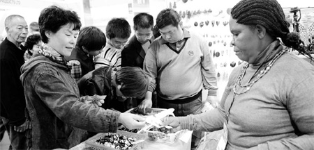 Chinese customers look for handicrafts at a stall from Uganda at an exhibition in Yiwu, Zhejiang province On Oct 25, 2010. [China Daily] 