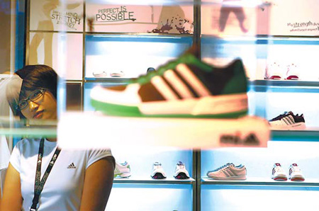 An Adidas clerk studies a display at a new store in Beijing. The Adidas Group said it is aiming for double-digit growth in annual sales in China through 2015. [Photo/Agencies]