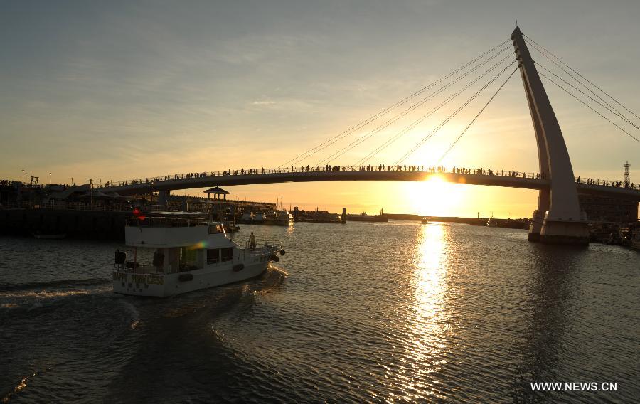 A yacht sails near the fisherman's wharf during the sunset in Danshuei District of Xinbei City, southeast China's Taiwan, Aug. 21, 2012. [Xinhua/Yin Bogu]