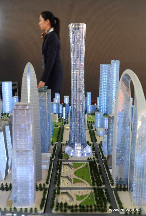 A staff member walks past a building model of the city's tallest skycraper in Beijing, capital of China, Sept. 19, 2011. 