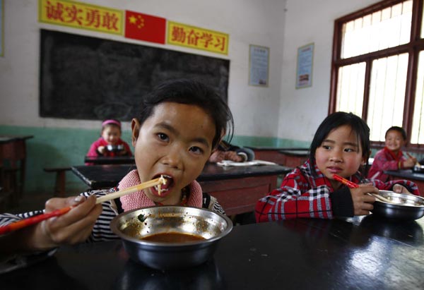 Schoolchildren eat their free lunch at Xinglong Primary School in a mountainous area of Bijie city, in Southwest China's Guizhou province, last month. [ Photo / China Daily ]