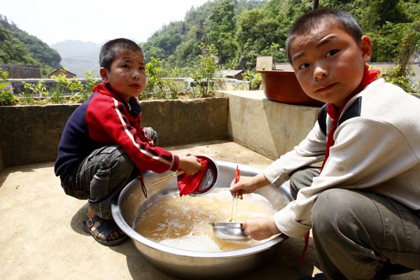 Two boys at Xinglong Primary School help with the dishes after lunch. [ Photo / China Daily ]