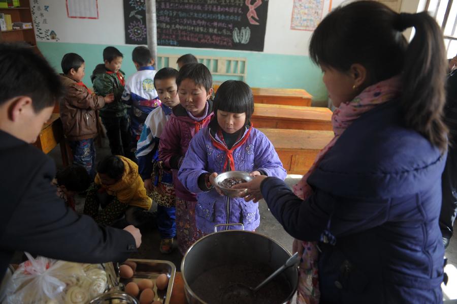 Students queue up to get their lunch at the classroom of Shimen central primary school in Tianzhu Tibetan Autonomous Prefecture, northwest China's Gansu Province, March 12, 2012.[Photo/Xinhua]