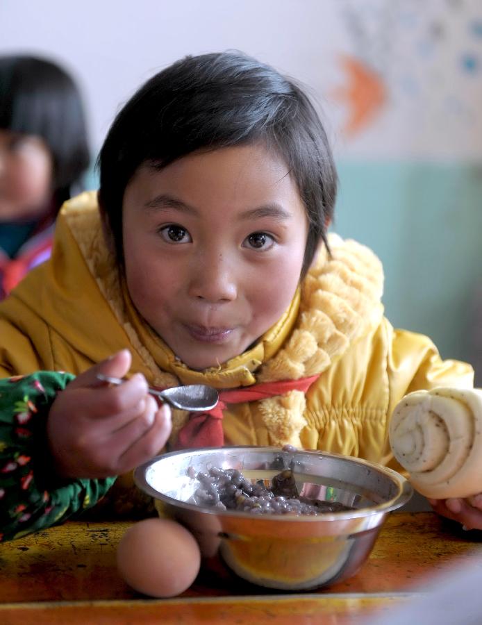 He Cunlian, a pupil of Tu ethnic group, takes her lunch at the classroom of Shimen central primary school in Tianzhu Tibetan Autonomous Prefecture, northwest China's Gansu Province, March 12, 2012. 